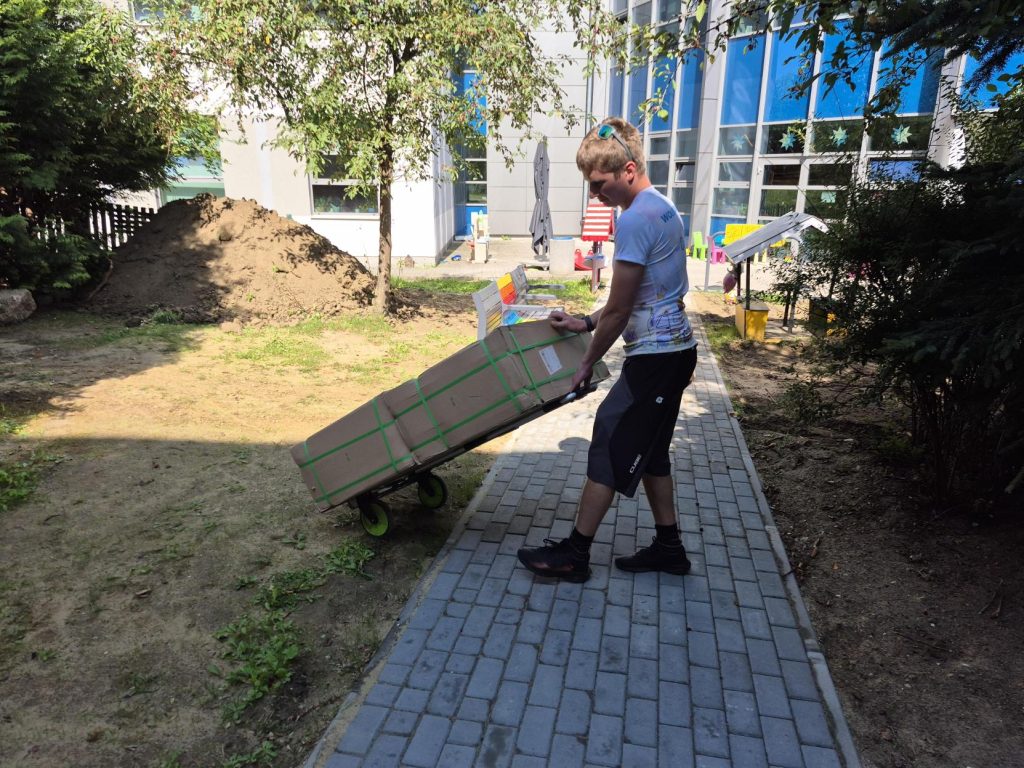 Wolontariusz porządkuje teren ogrodu sensorycznego i przygotowuje rabaty do nowych nasadzeń.